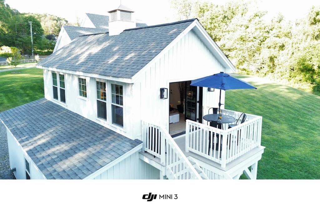 een wit huis met een tafel en een paraplu bij Perch, for work or wandering the Litchfield Hills in Southbury