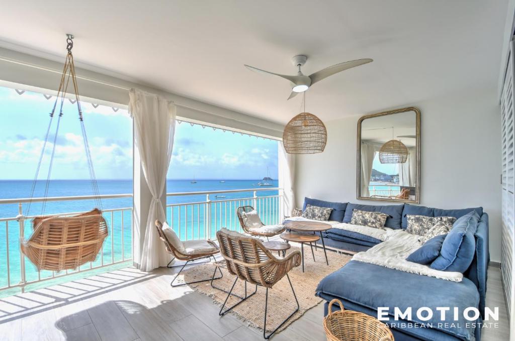 uma sala de estar com um sofá azul e uma varanda em Appartement 2 chambres sur la plage de grand case em Grand Case