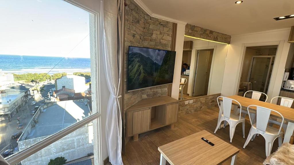 a living room with a large window and a table with chairs at Chiara's Apartament panoramico in Santa Teresita