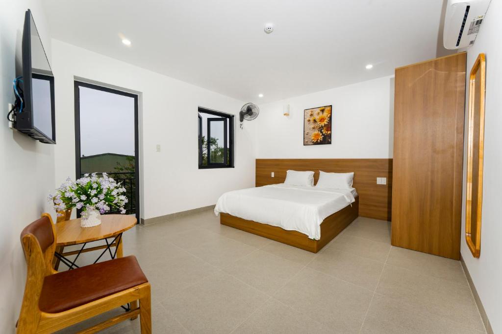 ein Schlafzimmer mit einem Bett, einem Tisch und einem Stuhl in der Unterkunft Phú Châu Motel in Phú Vang