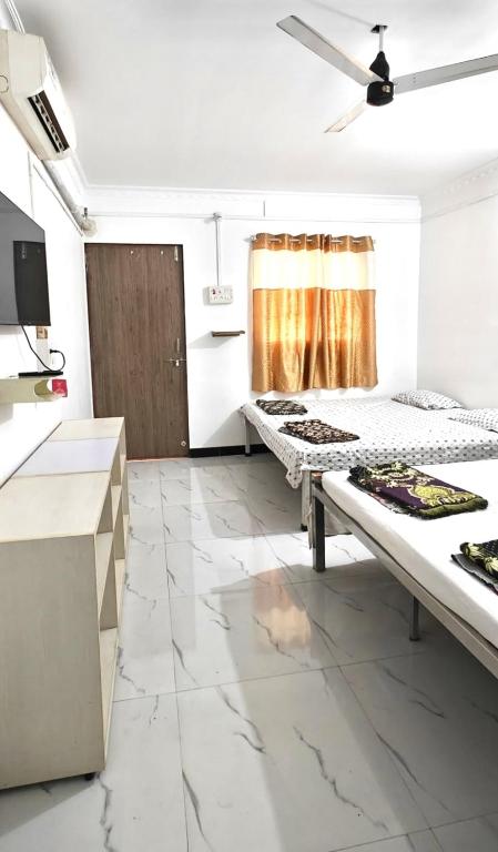 a kitchen with two beds in a room with marble floors at Kulswami Cottage Alibag in Alibaug