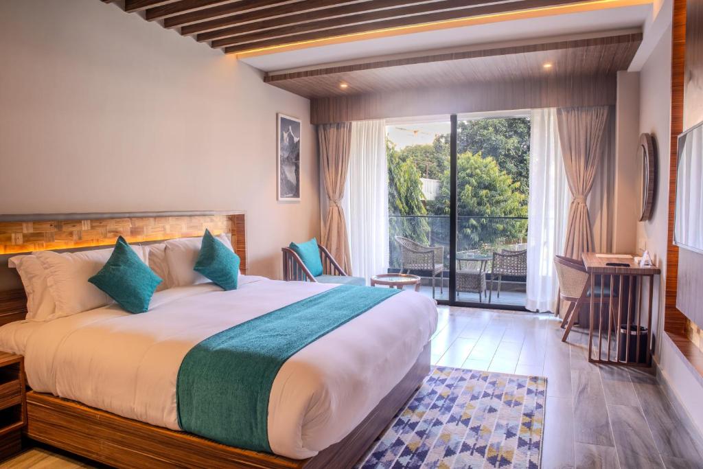 a bedroom with a large bed and a balcony at Soaltee Westend Lakeside Pokhara in Pokhara