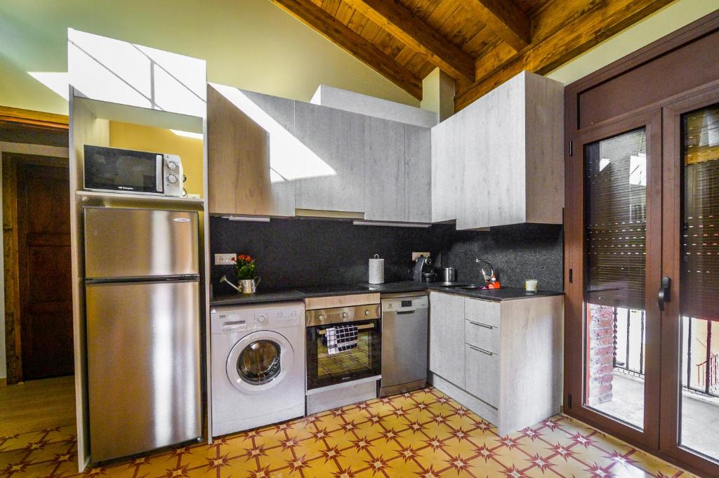 cocina con nevera, lavadora y secadora en Apartaments Cal Xic, en Bellver de Cerdanya 