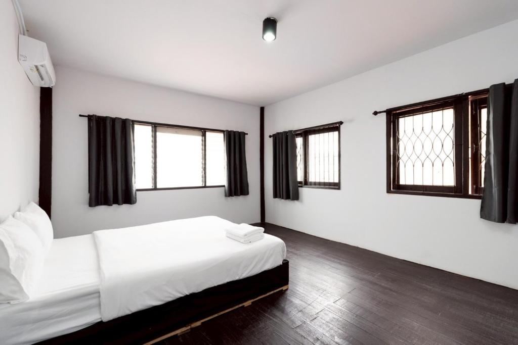 a bedroom with a bed with white sheets and windows at XX Mitr Khaosan Bangkok in Bangkok