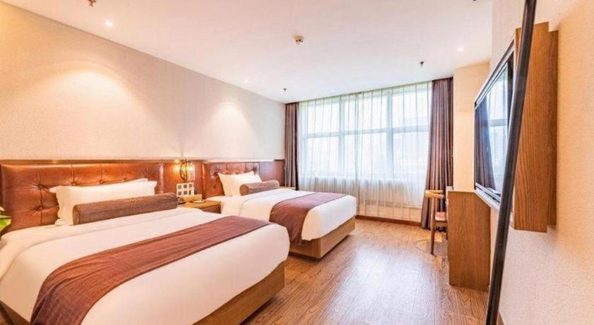 a hotel room with two beds and a television at James Joyce Coffetel Shijiazhuang the Mixc Jinyuan Tower Airport Bus in Shijiazhuang