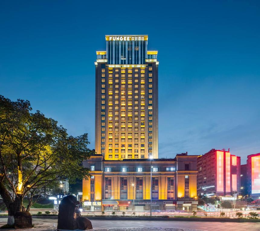 a large building with a lit up skyscraper at FunGee X Hotel Wanzhou Wanda Plaza Branch in Wanzhou