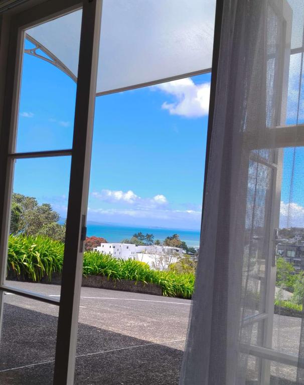 a view of the ocean from a window at Bayview Holiday Flat in Auckland