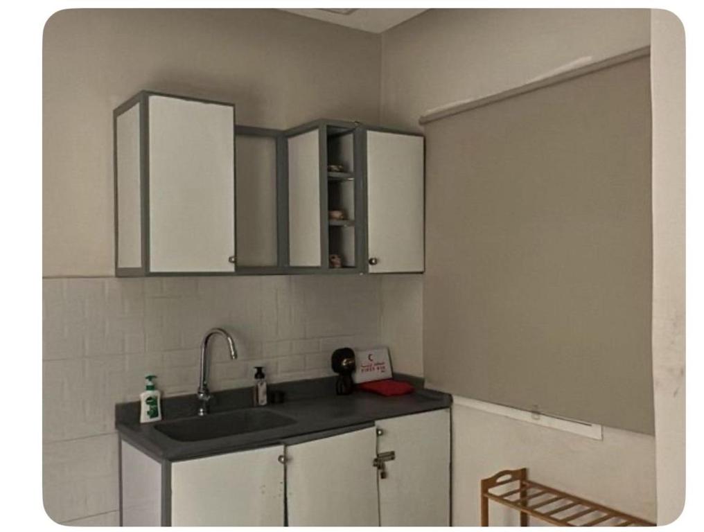 uma cozinha com armários brancos e um lavatório num quarto em شقة غرفة وصالة em Al Khobar