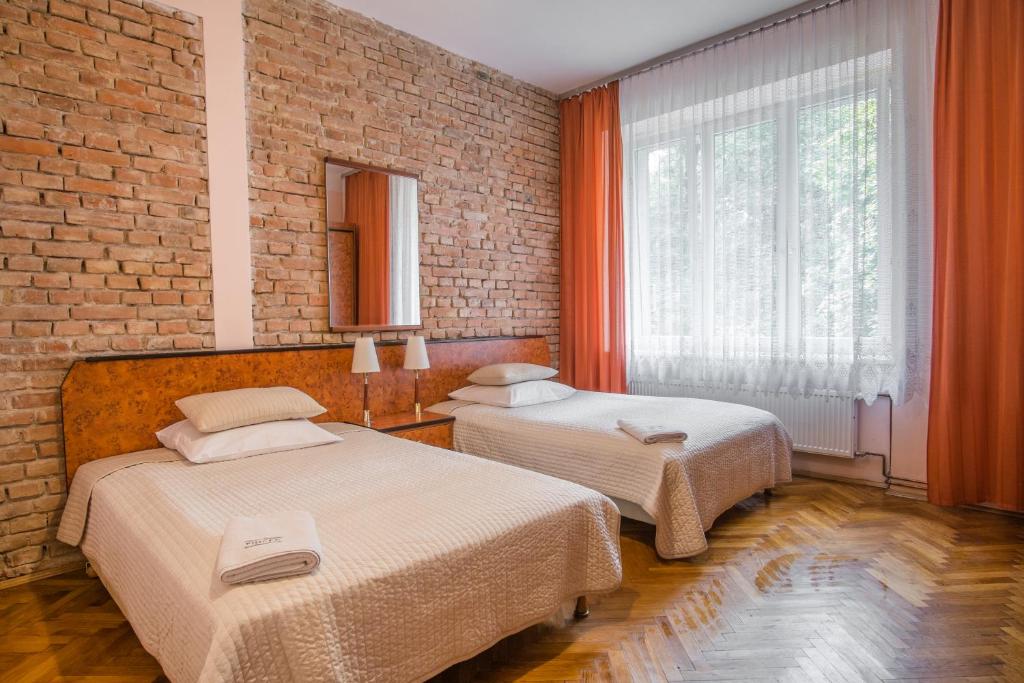sypialnia z 2 łóżkami i ceglaną ścianą w obiekcie Finger Guest Rooms w Krakowie