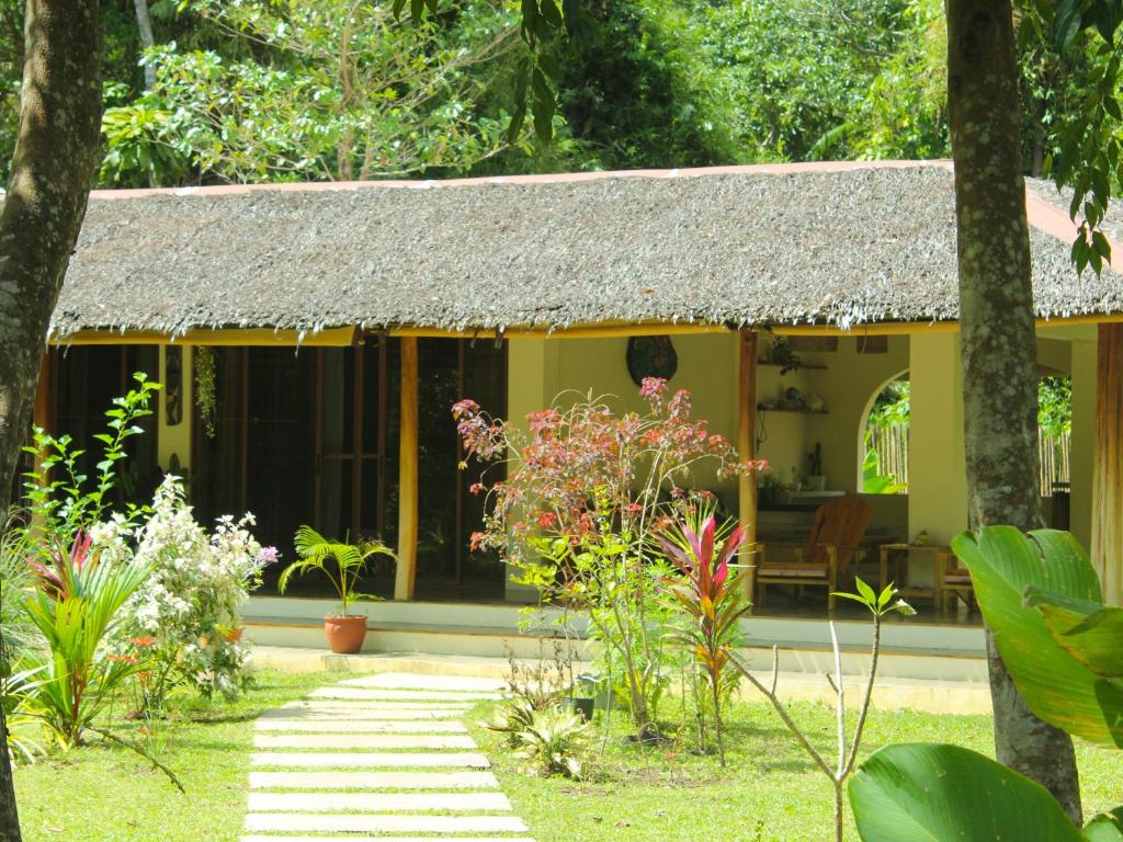 公主港Payapa garden Nagtabon Beach的花园中带茅草屋顶的房子