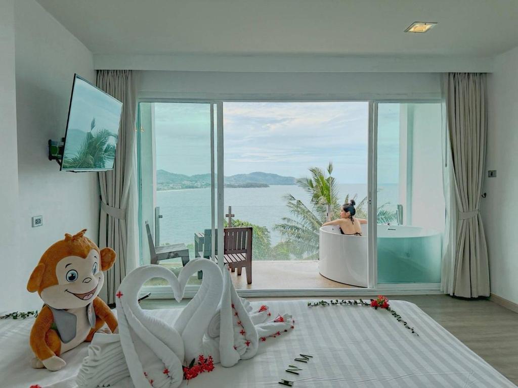 Secret Cliff Resort & Restaurant - SHA Plus في شاطئ كارون: غرفة نوم مع دمية الدب يجلس على سرير