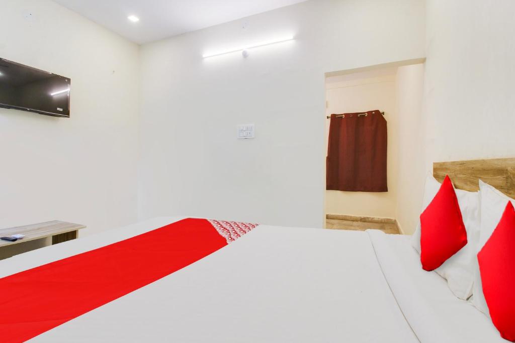 a bedroom with a white bed with red pillows at Hotel O R Squre Inn in Hyderabad