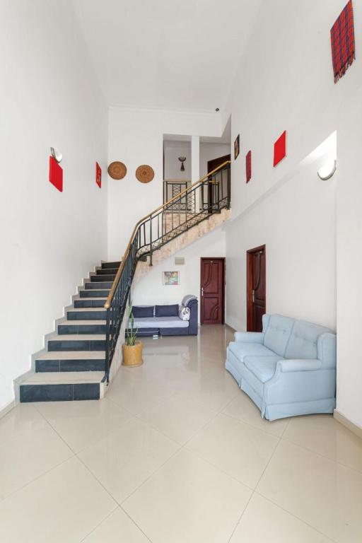 a living room with a blue couch and stairs at Entebbe Hotel in Entebbe