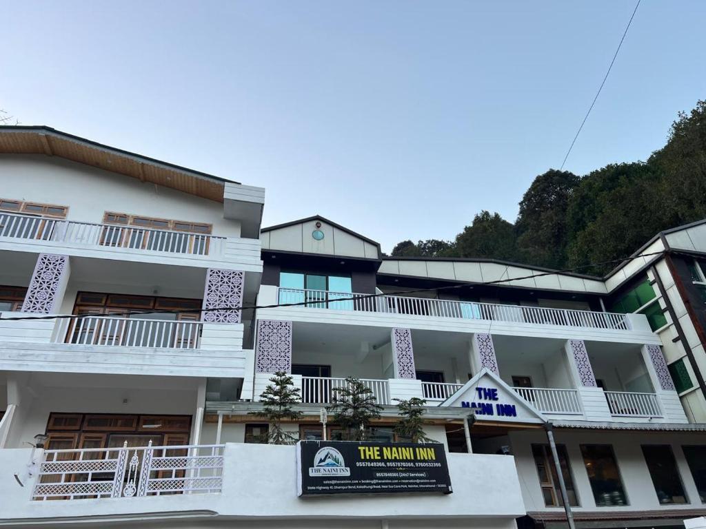 a white building with a sign in front of it at The Naini Inn By ASPien Hotels in Nainital