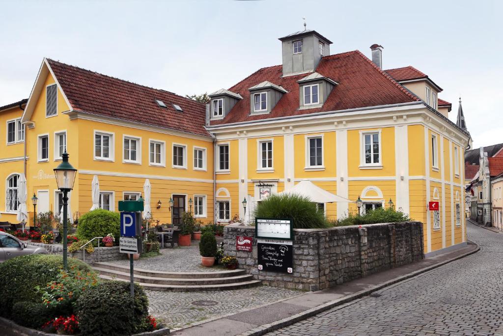 um edifício amarelo com um telhado vermelho numa rua em Babenbergerhof em Ybbs an der Donau