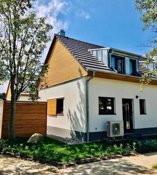 a white house with a fence and a tree at Ferienhaus BUG - zwischen Bodden und Meer in Dranske