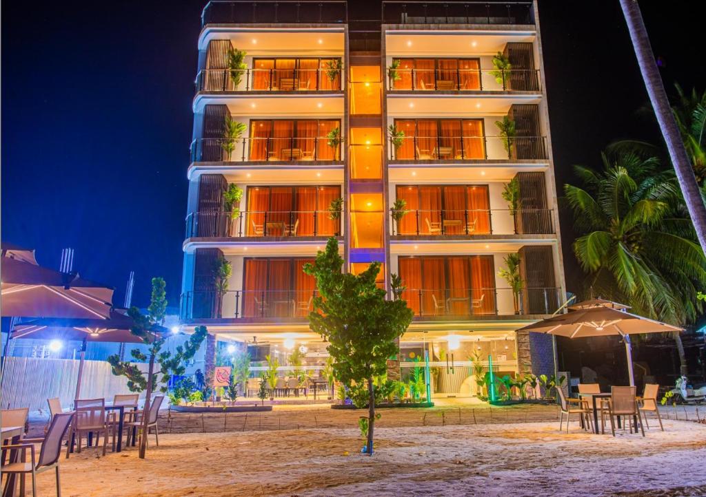 a hotel with tables and umbrellas in front of it at Lonuhiri at Dhigurah in Dhigurah