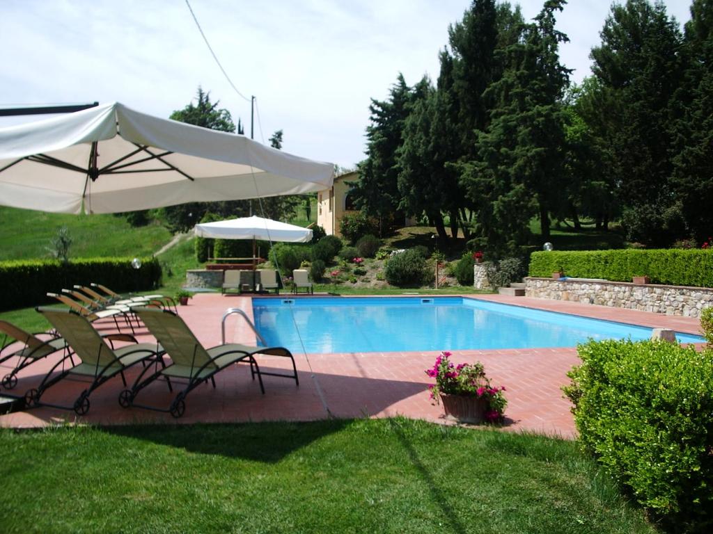 - une piscine avec 2 chaises et un parasol dans l'établissement Agriturismo San Francesco Amalia and Anna, à Orciatico