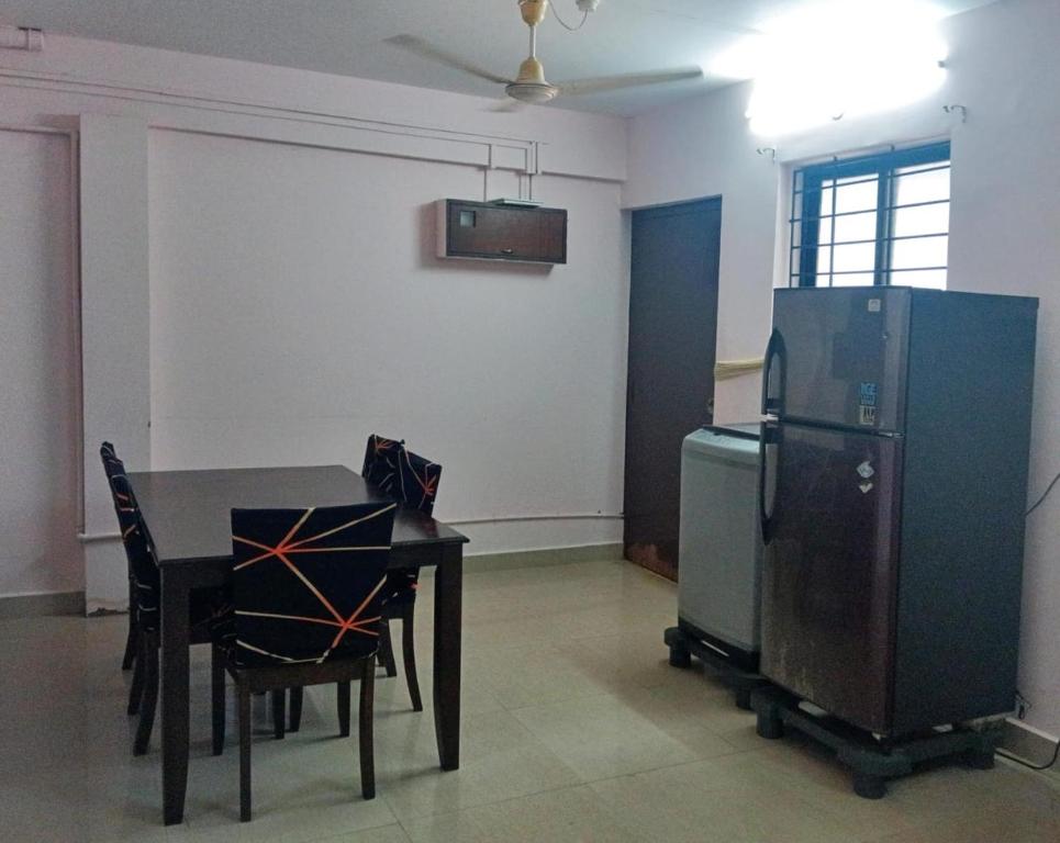 マンガロールにあるMohtisham Oasis Apartmentのテーブルと冷蔵庫のあるダイニングルーム