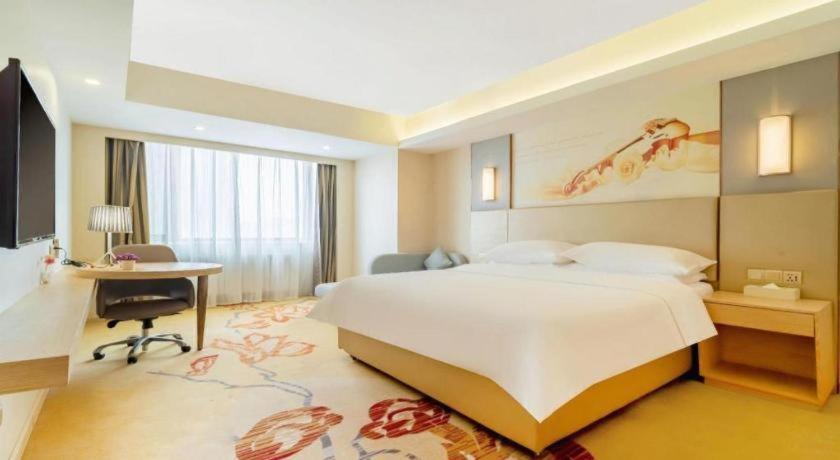 um quarto de hotel com uma cama, uma escrivaninha e um computador em Vienna Hotel Harbin Central Avenue em Harbin