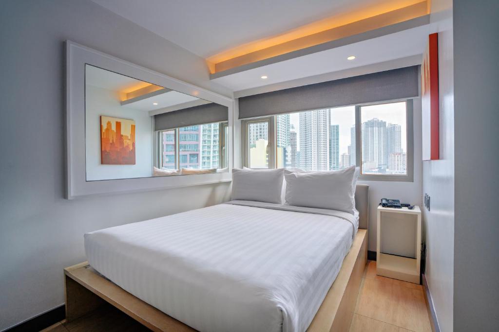 a bedroom with a large white bed with windows at The Mini Suites Eton Tower Makati in Manila