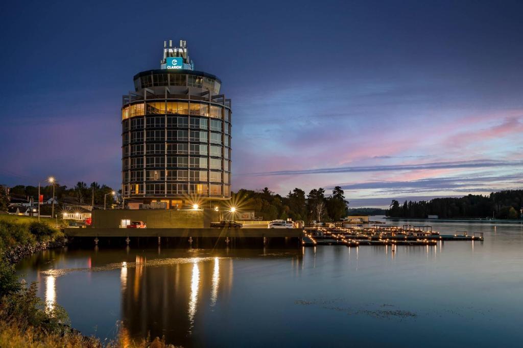 a building with a clock tower next to a body of water at Clarion Lakeside Inn & Conference Centre in Kenora