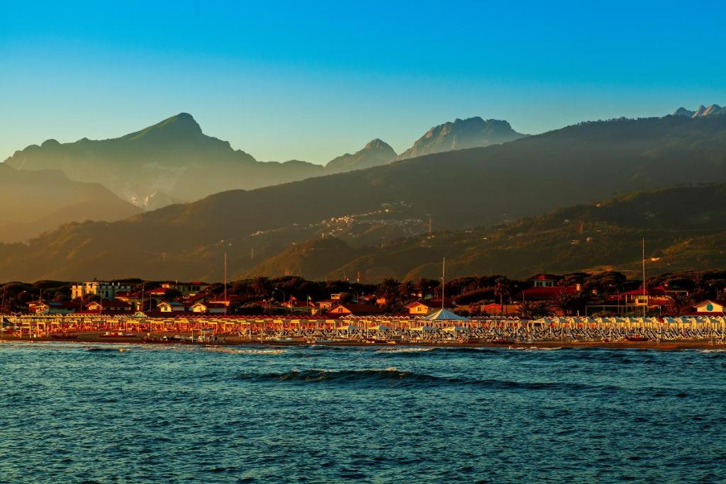 un grupo de personas de pie en una playa cerca del agua en Casa Rinchiosa, en Marina di Carrara