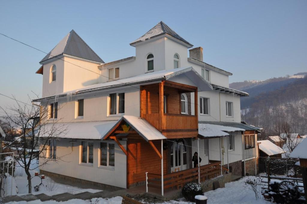 uma casa grande com neve no chão em Яблучко em Yaremche