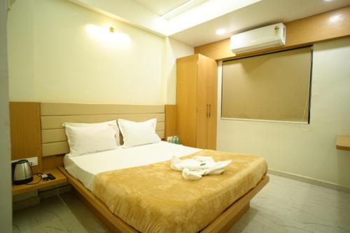 a hotel room with a bed with a towel on it at Hotel Sai Pratham in Shirdi