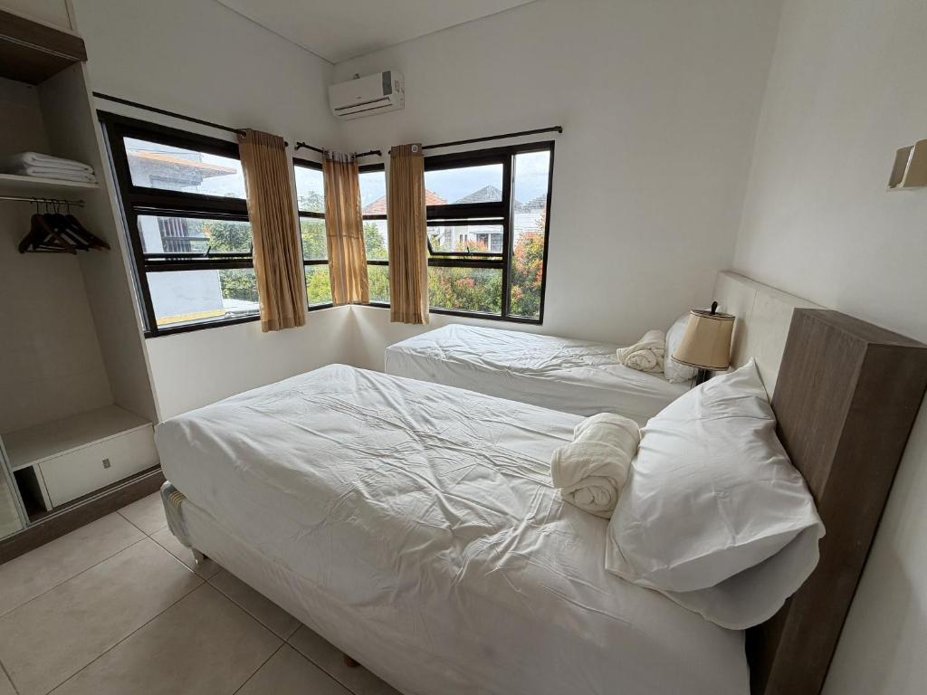 two beds in a room with two windows at Pandan de Bali in Ungasan