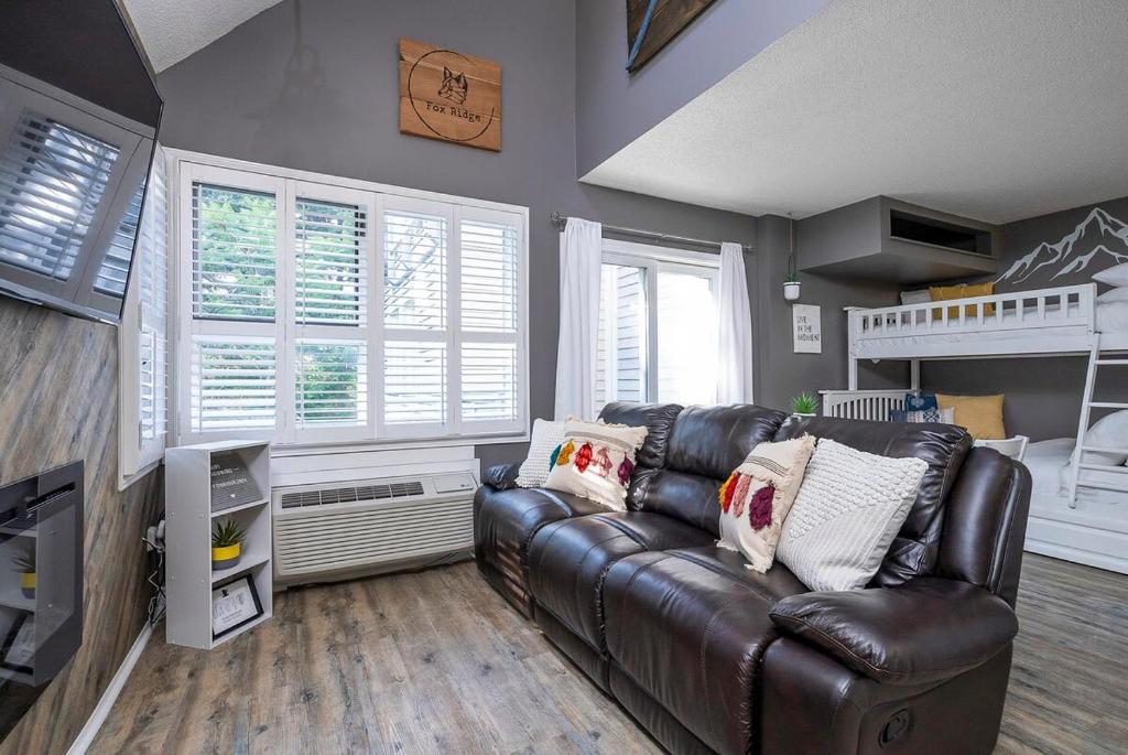 ein Wohnzimmer mit einer Ledercouch und einem Etagenbett in der Unterkunft Fox Ridge - Ski-In-Out Pool Hot Tub Shuttle in Blue Mountains