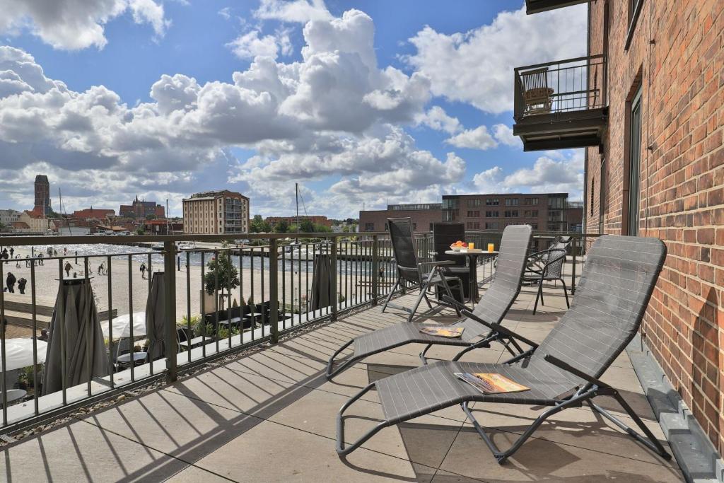 a patio with chairs and a table on a balcony at Ohlerich Speicher App_ 02 in Wismar