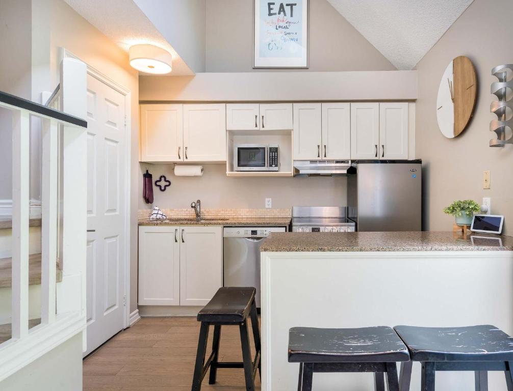 a kitchen with white cabinets and a counter with stools at Whispering Pines - Ski-In-Ou Pool Shuttle in Blue Mountains