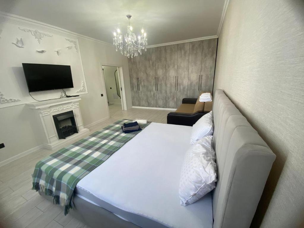 Квартира посуточно في أستانا: غرفة نوم مع سرير ومدفأة وتلفزيون