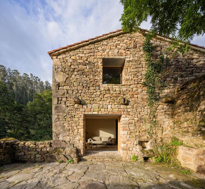 a large stone building with a couch in the doorway at Casa Mínima retiro Passivhaus in Selaya