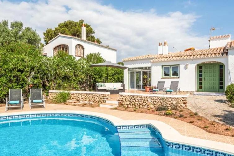a villa with a swimming pool in front of a house at Villa Cau Ventos in Cala Galdana