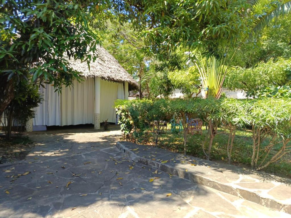 a house with a thatched roof and a garden at Daijan villa in Ukunda