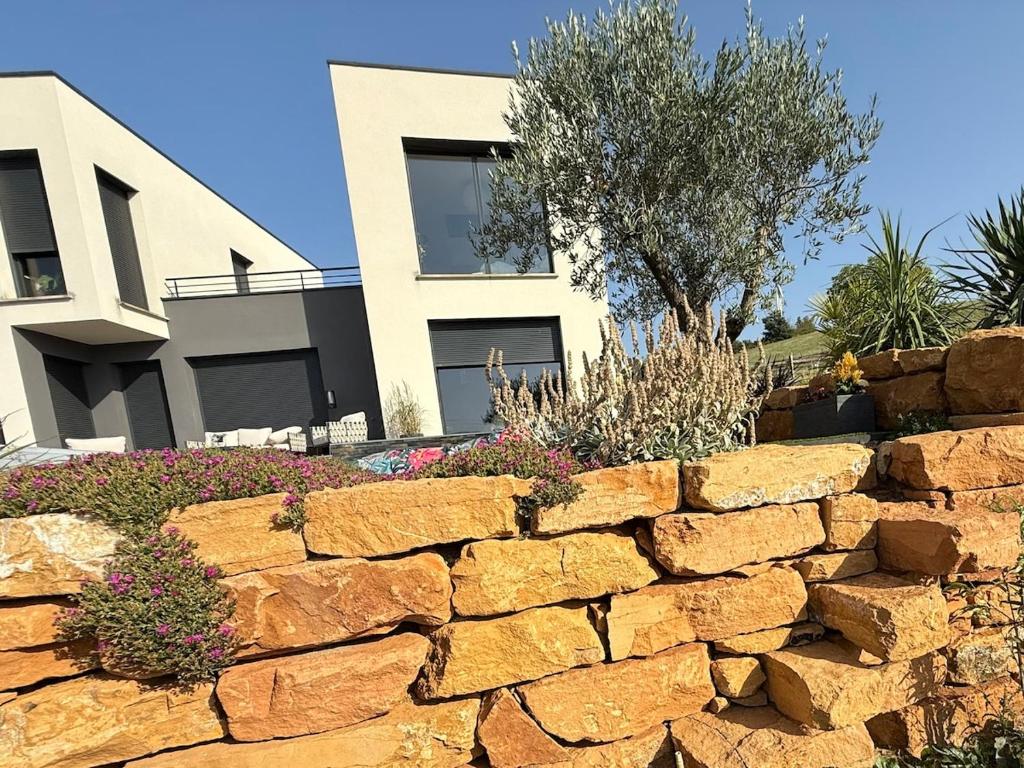 a stone retaining wall in front of a house at Studio cosy au Crêt du Chardon in Chambost-Allières
