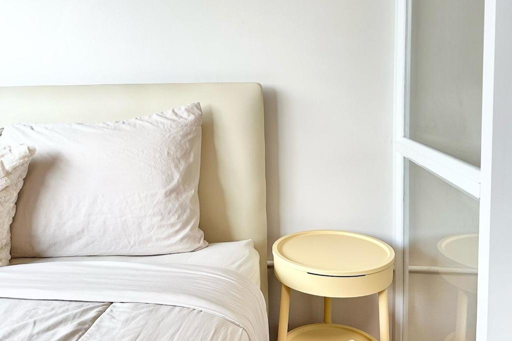 a bed with a white pillow and a stool next to it at Lykke Room Poppular Condo P1 in Ban Bang Phang