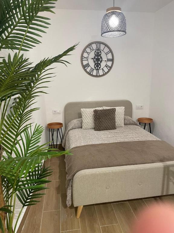 ein Schlafzimmer mit einem Bett und einer Uhr an der Wand in der Unterkunft Apartamento Mamalú Jerez in Jerez de la Frontera