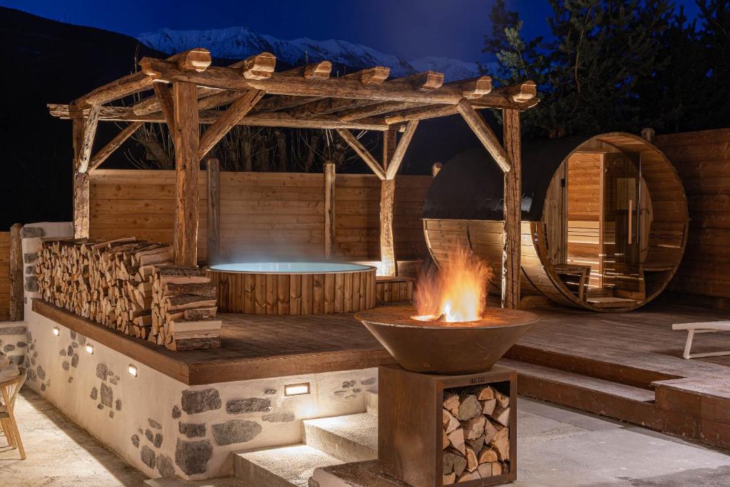 Una fogata en un patio con una pérgola de madera. en Chalet La Louvetiere 14 persones 6 chambres, en Le Bez