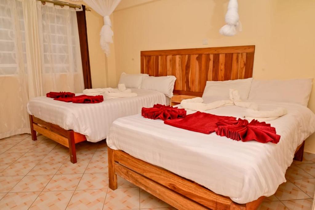 Dos camas con rosas rojas en una habitación. en Snow Peak Hotel in Chogoria, en Mwangarimwe
