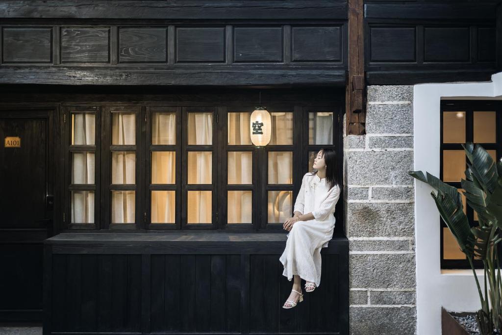 een vrouw die op de vensterbank van een gebouw zit bij Dongsheng Design Hotel in Dali in Dali