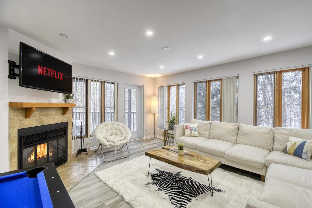 een woonkamer met een witte bank en een tv bij Pool Table - Elegance - Comfort - Le Chic Boreal in Saint-Jovite