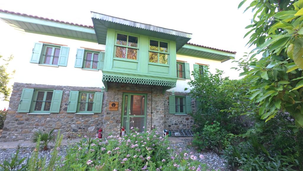 una casa con persiane verdi e fiori di fronte di Menekse a Koycegiz