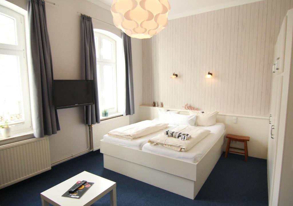 Kapitaenshaus-Lassen-Zimmer-Amistad في فيسترلاند: غرفة بها سرير أبيض وجهاز تلفزيون ونوافذ