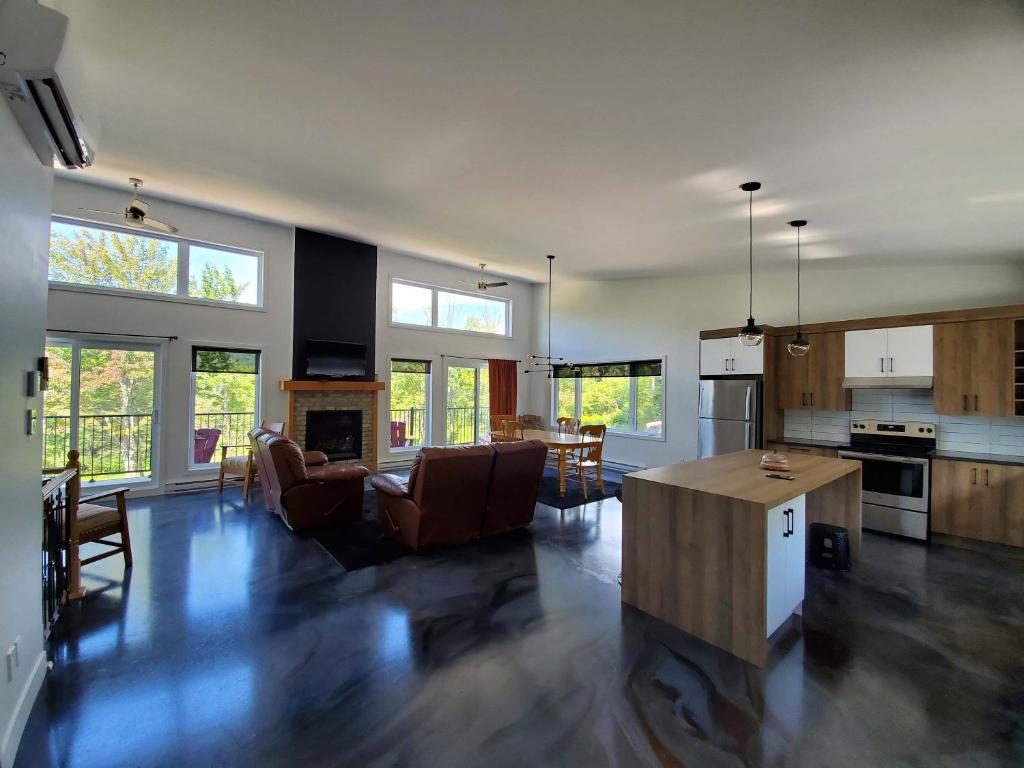 a living room with a kitchen and a living room with a fireplace at Relaxation & Comfort - Chalet Sault a la Puce in Sainte-Anne-de-Beaupré
