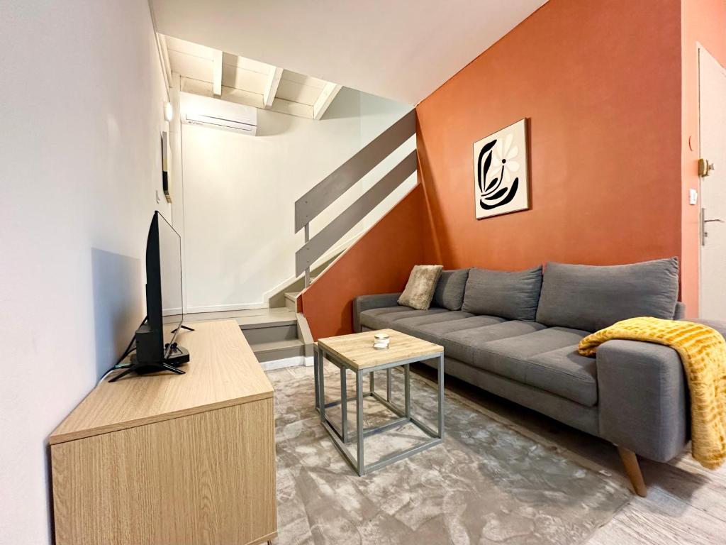 een woonkamer met een bank en een tv bij Le Cocon Urbain - Spacieux - Hyper Centre in Mont-de-Marsan