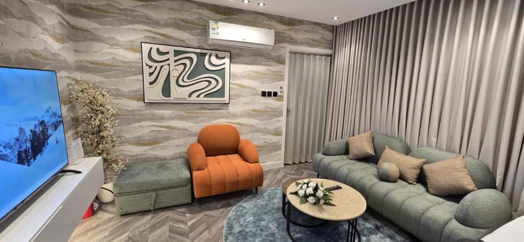 een woonkamer met een bank, stoelen en een tv bij Elegant studio in Riyad