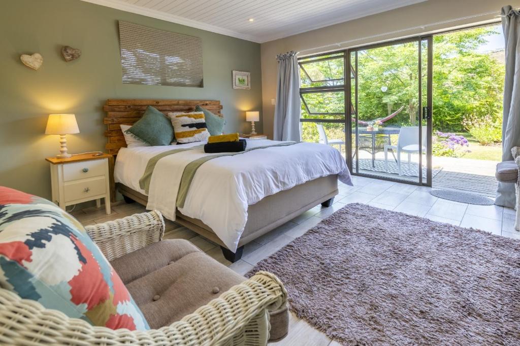 1 dormitorio con 1 cama grande y patio en En-suite, private room, free WIFI in Plett, en Plettenberg Bay